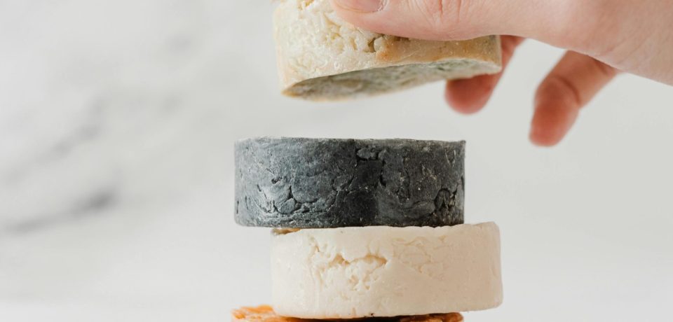 A hand placing eco-friendly soap bars in a stack, promoting zero waste and sustainable living.